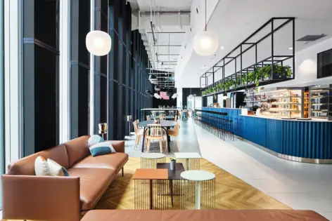 Seating in the restaurant, such as sofas and chairs with tables. Bar counter on the right.