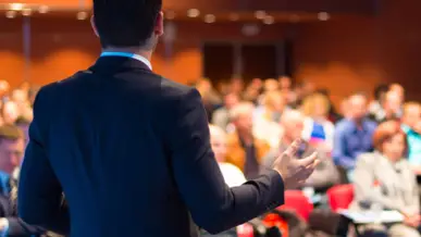 Blick von hinten auf Mann im Businessoutfit. Vor ihm ein großer Raum mit vielen Menschen. Blick von hinten auf Mann im Businessoutfit. Vor ihm ein großer Raum mit vielen Menschen.