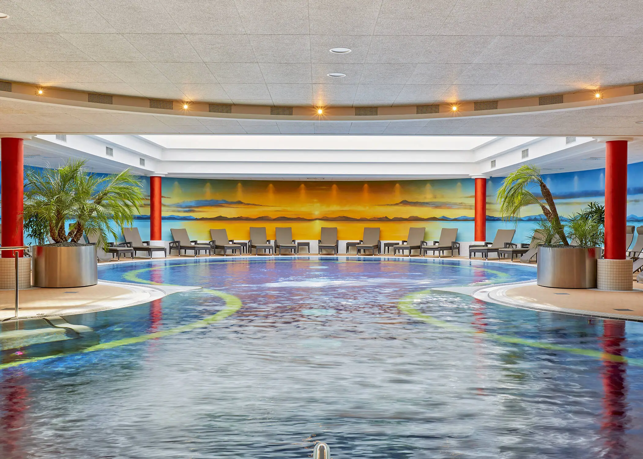 Schwimmbad mit einem großen Pool und Liegestühlen am Rand.