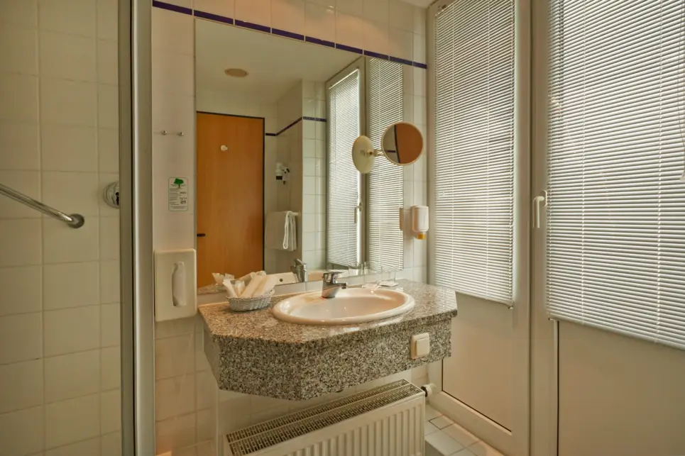 Lavabo en el cuarto de baño. Hay una ducha junto al lavabo.