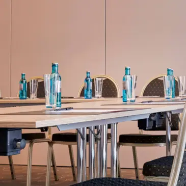 Nahaufnahme auf einen Tisch im Tagungsbereich auf  dem Wasserflaschen stehen.