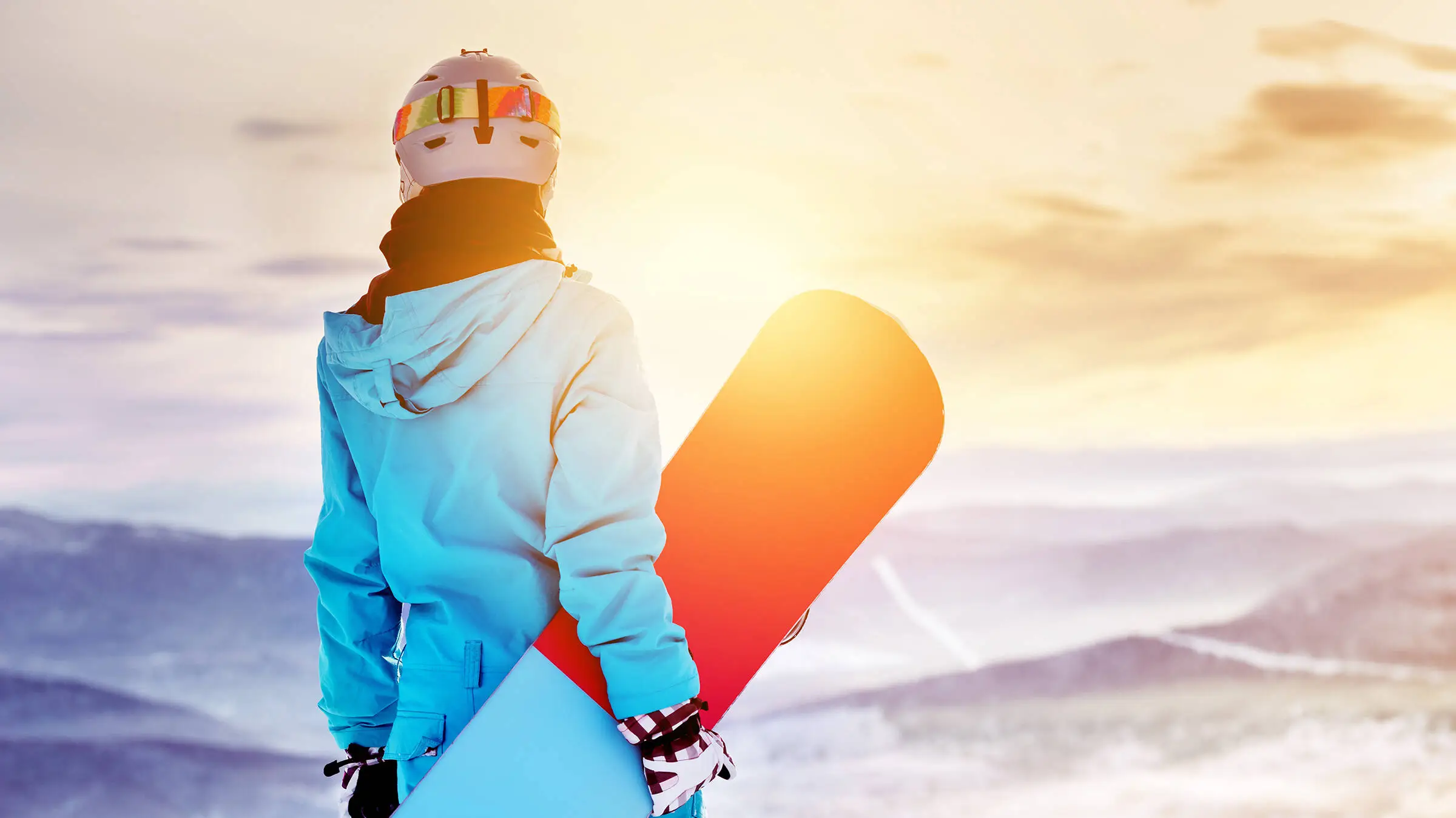 Ein Snowboarder steht mit seinem Snowboard in der Hand.