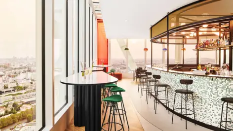 Tables et tabourets de bar devant de grandes fenêtres donnant sur la ville. Bar avec tabourets à droite.
