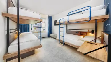 Hotelzimmer mit zwei Etagenbetten, kleinem Schreitbisch und einem Fernseher an einer Wand.. Hotelzimmer mit zwei Etagenbetten, kleinem Schreitbisch und einem Fernseher an einer Wand..