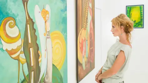 Eine Frau betrachtet Kunstgemälde in einer Galerie. Eine Frau betrachtet Kunstgemälde in einer Galerie.