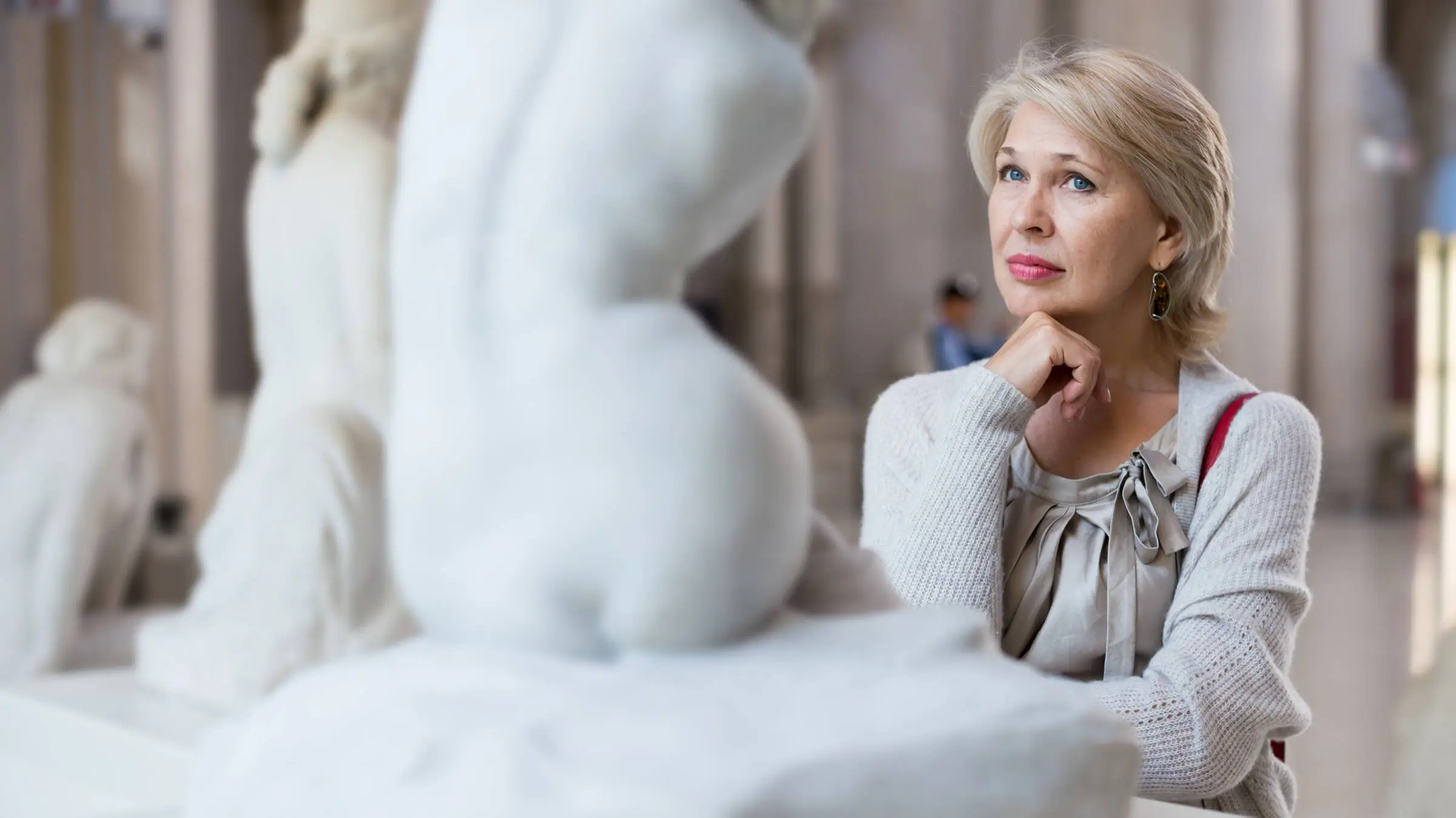 Mujer mirando una escultura blanca de una mujer