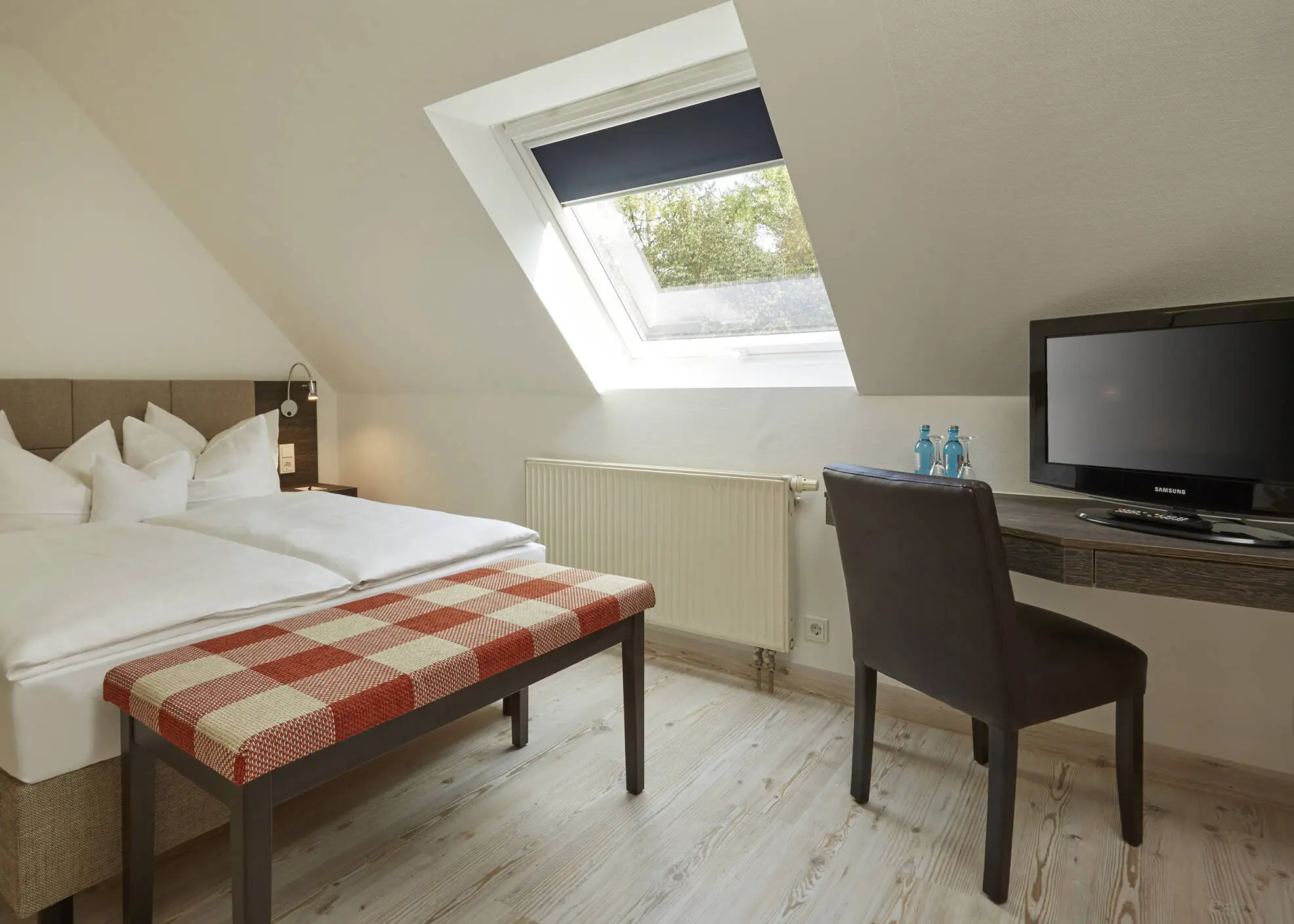 Hotelzimmer im Dachgeschoss mit einem Doppelbett und einem Schreibtisch.