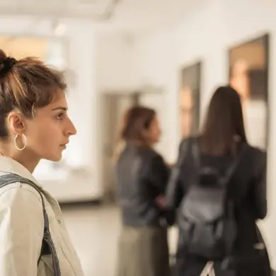 Three women look at pictures in a gallery