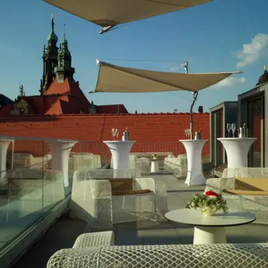 Dachterrasse mit weißen Sesseln und Tischen. Im Hintergrund steht das Grüne Gewölbe.