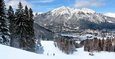 Winterlandschaft mit Blick auf dem weit entfernten Garmisch-Partenkirchen. Am Horizont sieht man das Gebirge.