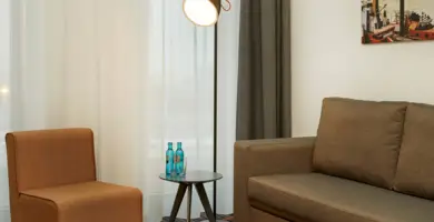 Sitzecke mit olivfarbenem Sofa und braunen Sessel im Hotelzimmer