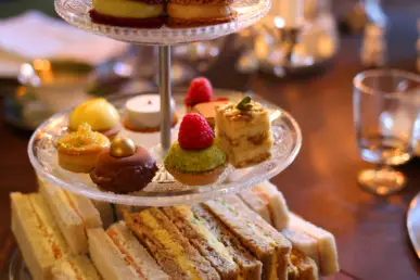Snacks such as sandwiches, macarons and petits fours on a tiered stand.