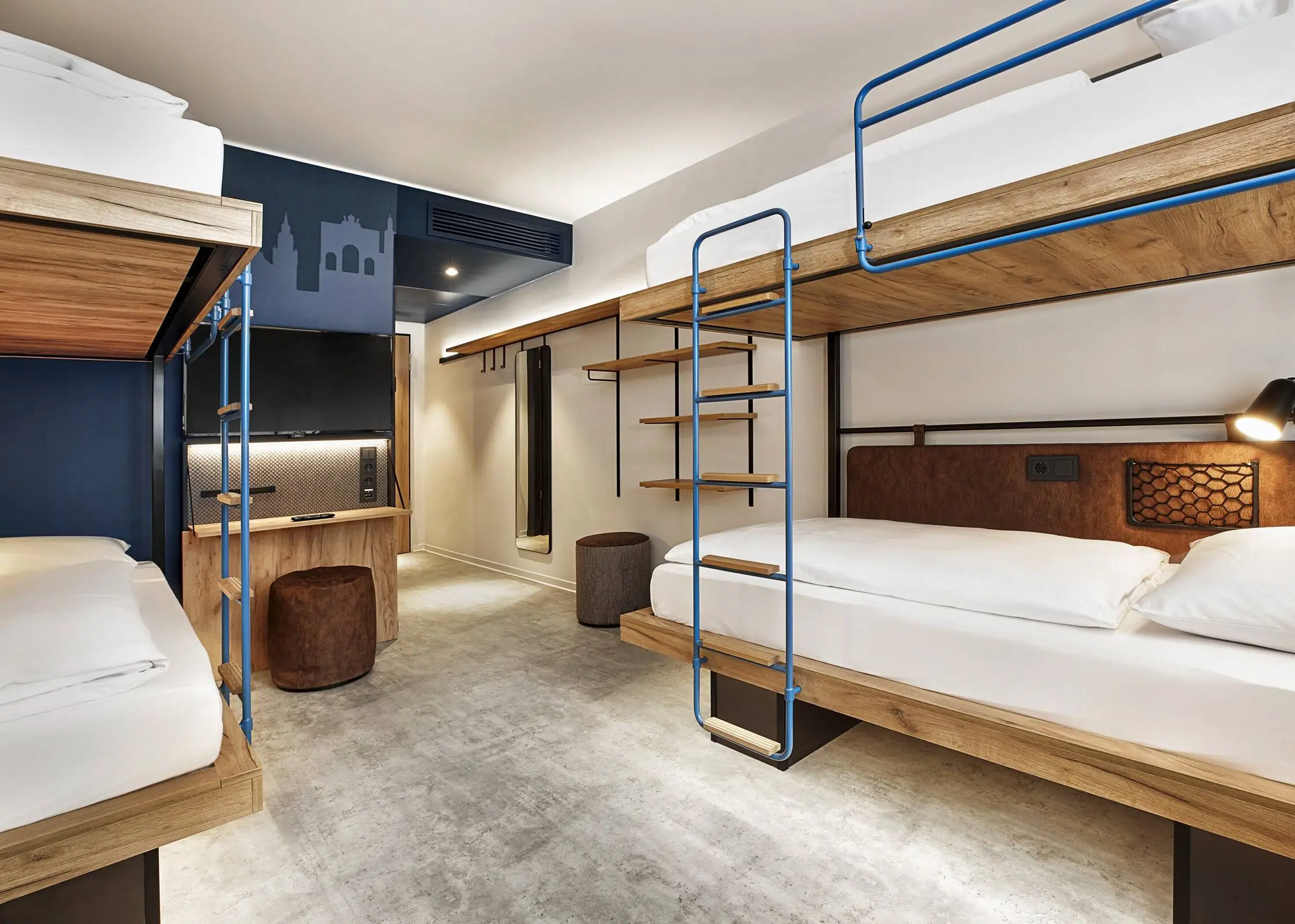 Hotelzimmer mit Doppelstockbetten. Das Zimmer ist farblich in einem dunklen Blau und Braun.