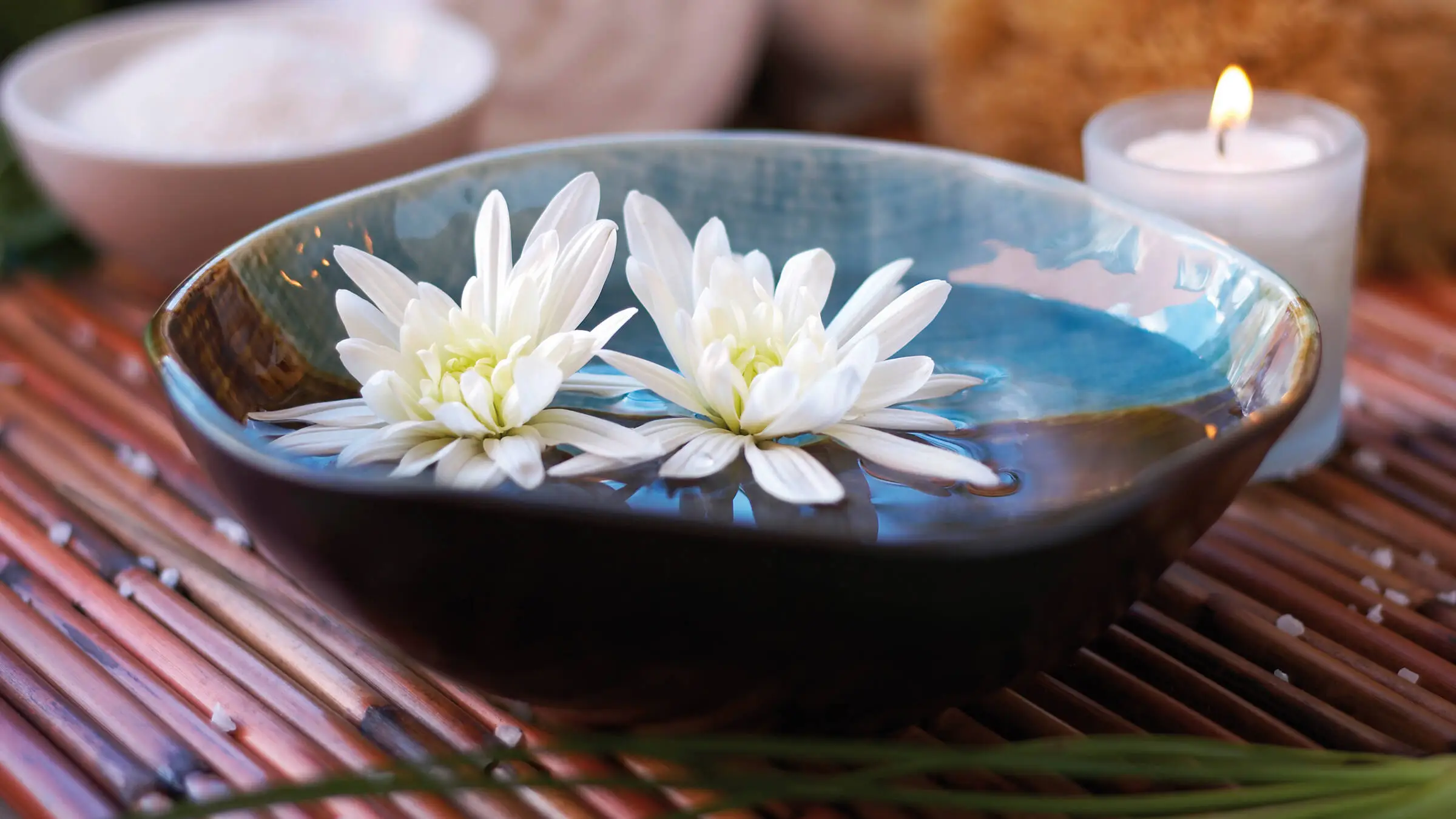 Gros plan d'un brûle-parfum avec deux fleurs blanches.