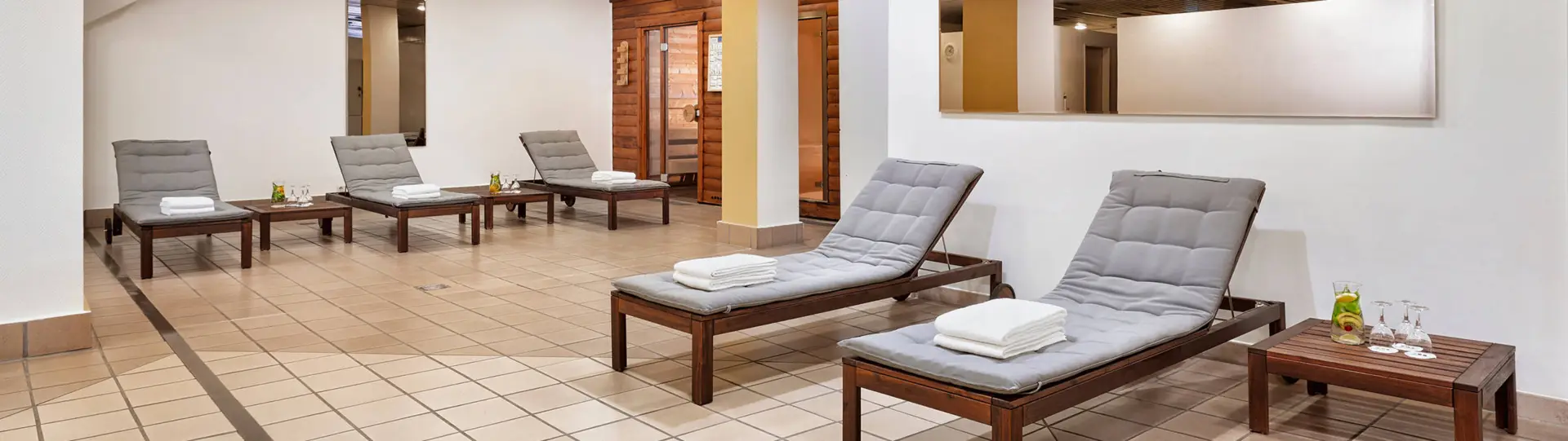 Ruheraum im Wellnessbereich mit Liegen. Im Hintergrund ist eine Sauna.