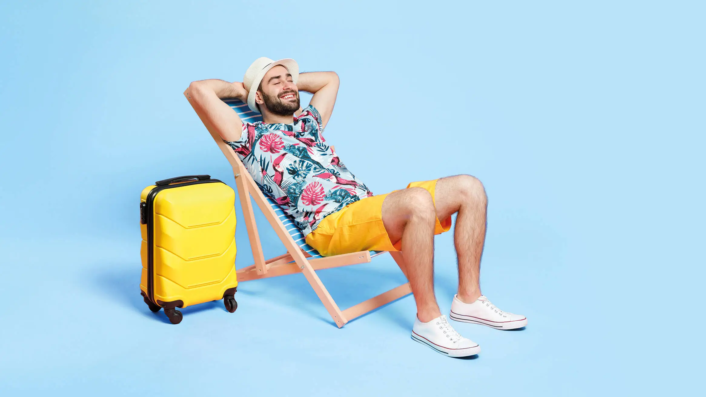 Man in summer outfit lying on a deckchair in front of a blue background.
