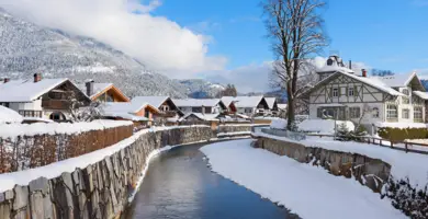 Garmisch-Partenkirchen im Winter mit einem halb zugefrorenen Fluss. Ringsherum stehen Fachwerkhäuser.