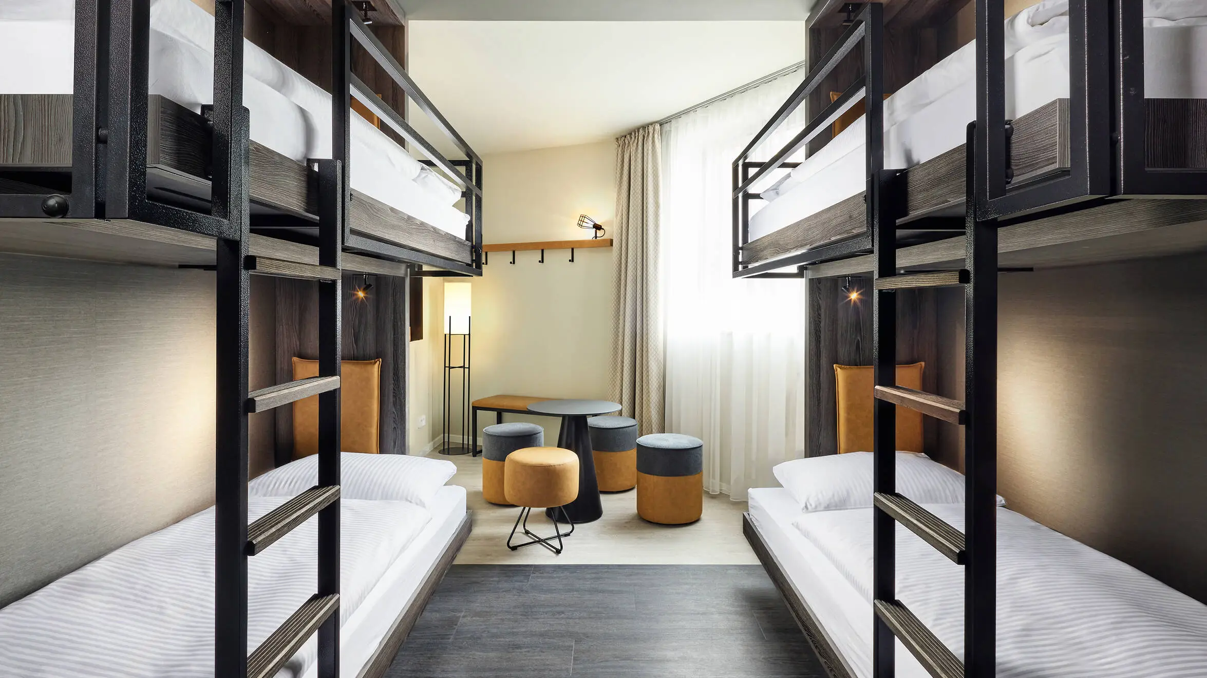 Hotelzimmer mit zwei Etagenbetten. In der Mitte steht eine kleine Sitzecke.