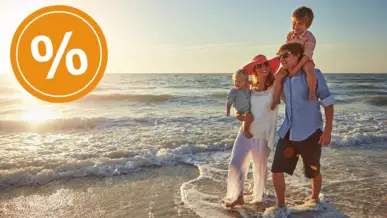 Eine Familie geht am Strand durch Wasser.
