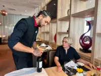 Nick Kobr präsentiert und öffnet den Wein der Ausbildungsverodnung gemäß am Tisch für Judith-Barbara Hindemitt