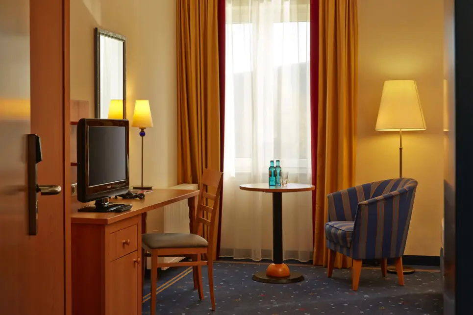 Vista a través de la puerta de la habitación del hotel con un sillón y un escritorio.