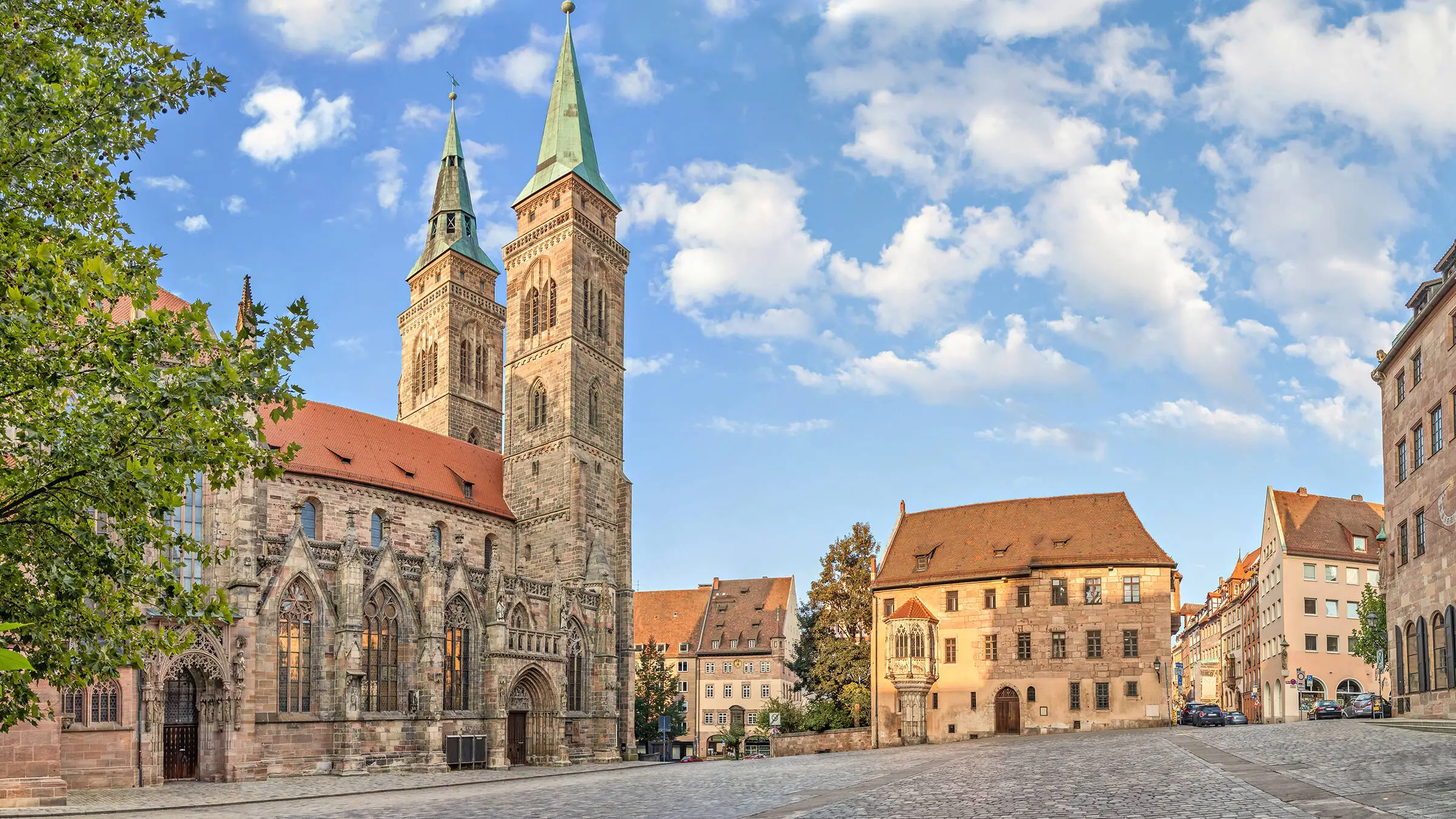 Square in Nuremberg with historic buildings and a church with two towers.