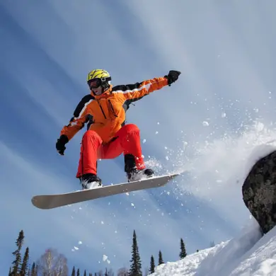 Un snowboarder saute par-dessus une pierre
