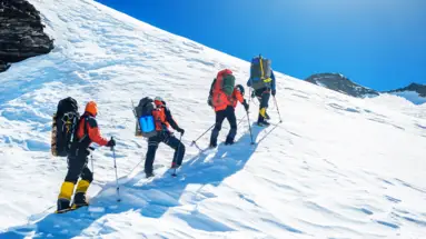 Vier Menschen wandern auf einem Berg im Schnee.