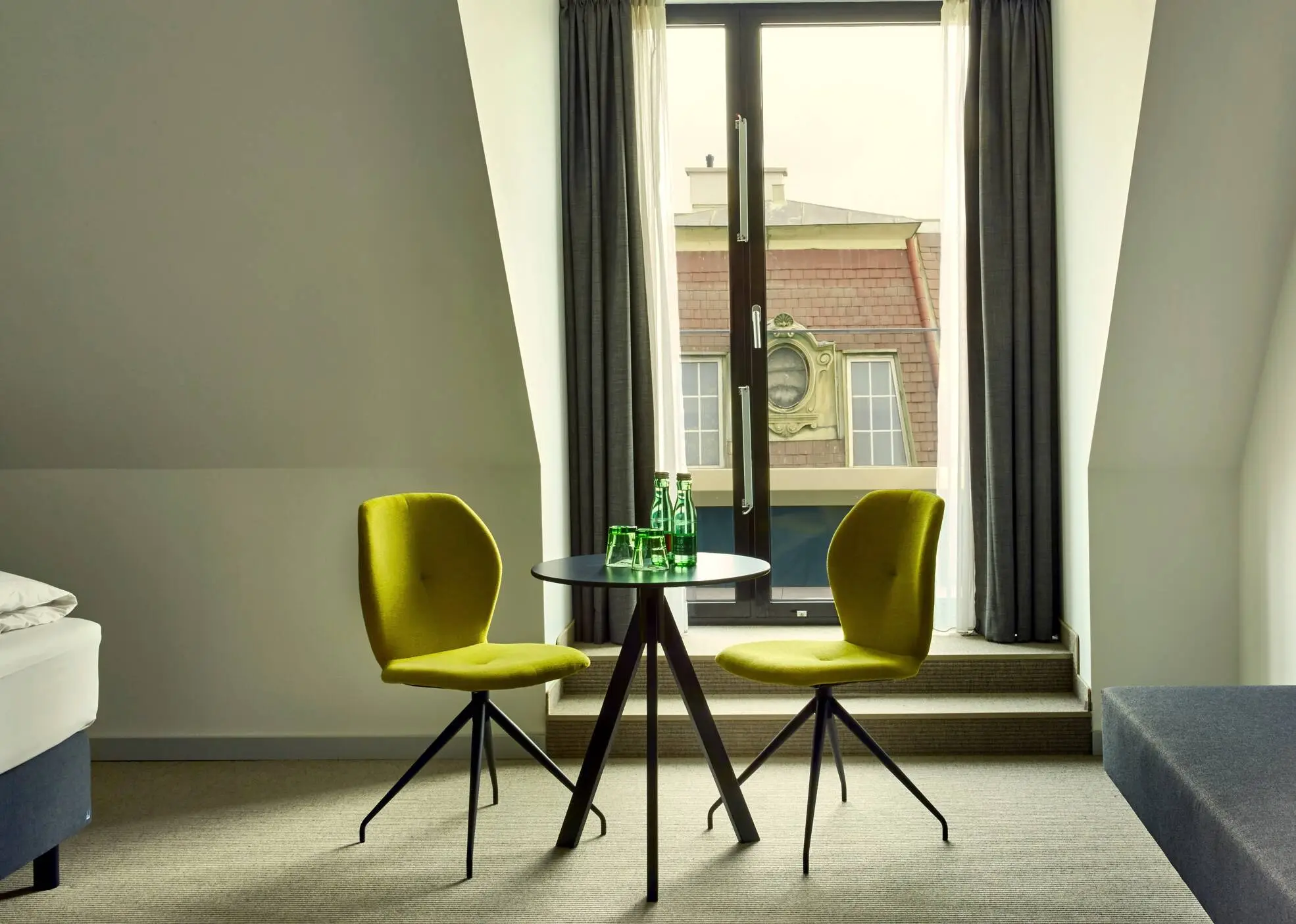 Small seating area in the hotel room in front of a large window.