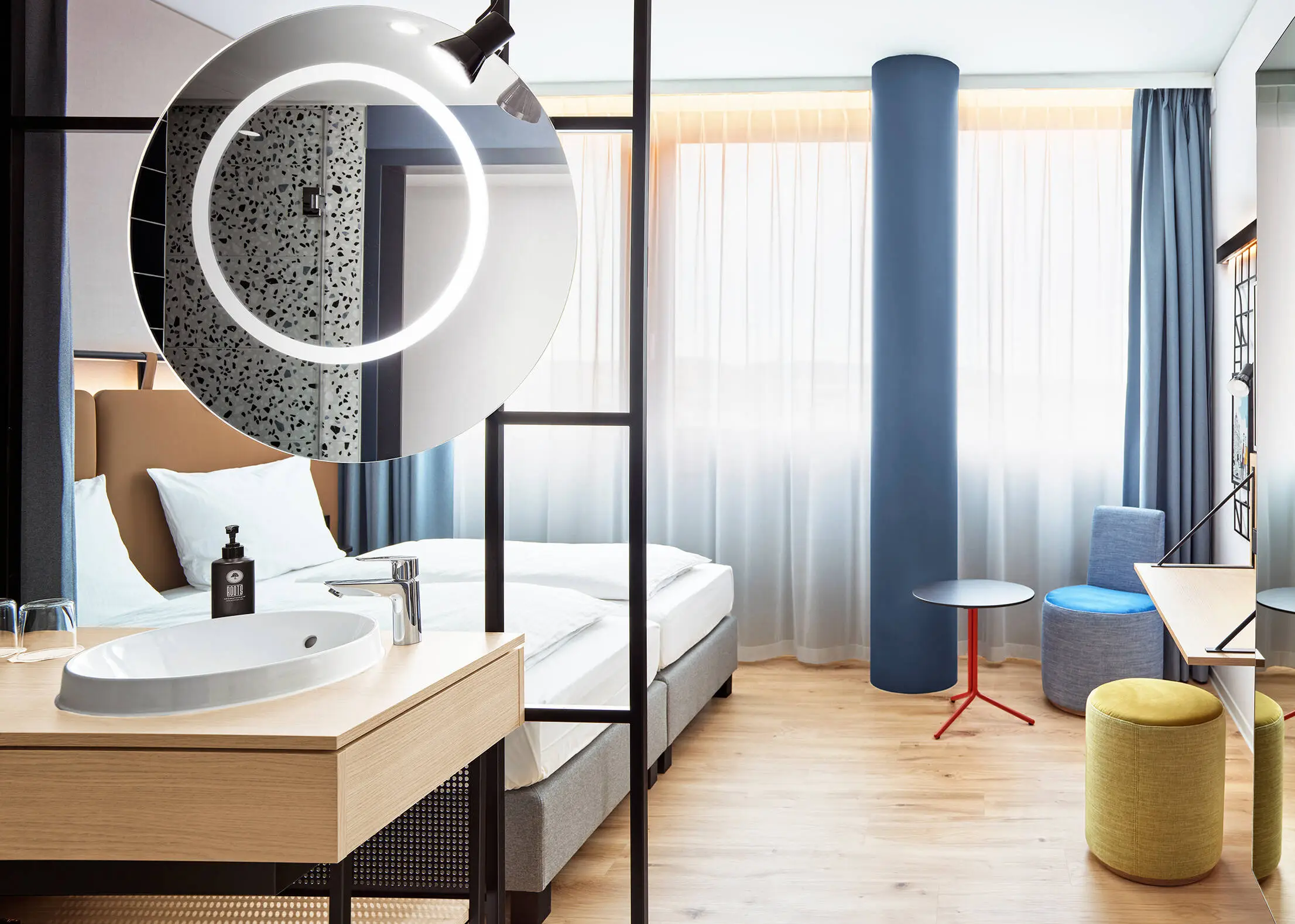 Hotelzimmer mit Doppelbett. In der Mitte steht eine kleine Sitzecke.