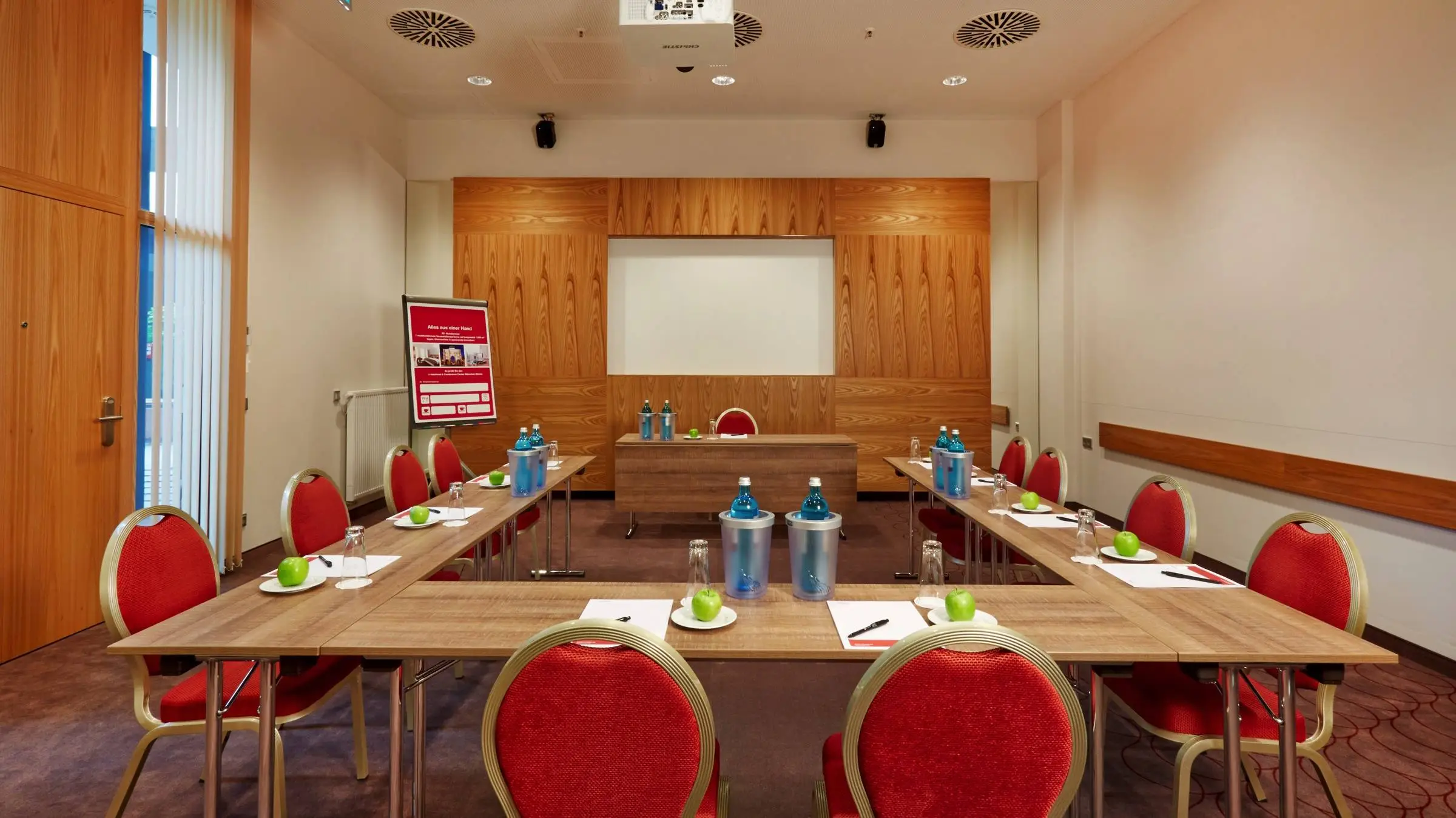 Kleiner Tagungsraum mit einer UForm Bestuhlung. An der Wand steht ein Rednertisch mit einem Flipchart daneben.