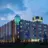 Außenansicht vom Hotel in den Abendstunden.  Auf dem Dach steht ein großer Würfel mit dem Namen H+ Hotel Leipzig-Halle.