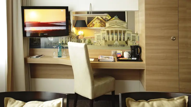Nahaufnahme von einem Schreibtisch im Hotelzimmer mit einem Fernseher und einem Stuhl.