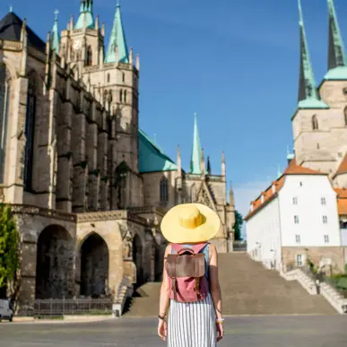 Eine Frau mit einem großen gelben Hut steht auf dem Domplatz und schaut zum Erfurter Dom.