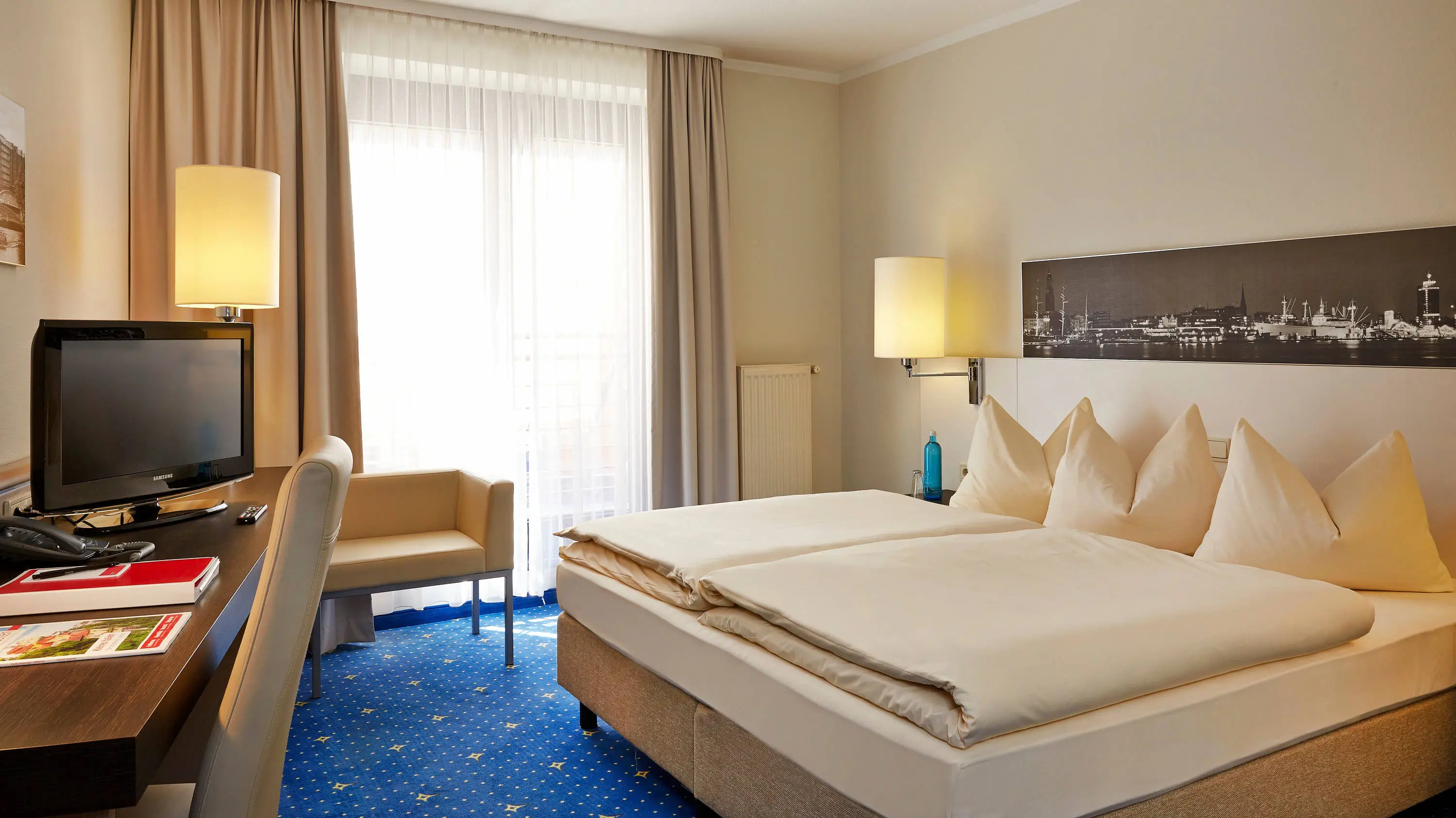 Hotelzimmer mit einem großem Doppelbett und einem Schreibtisch