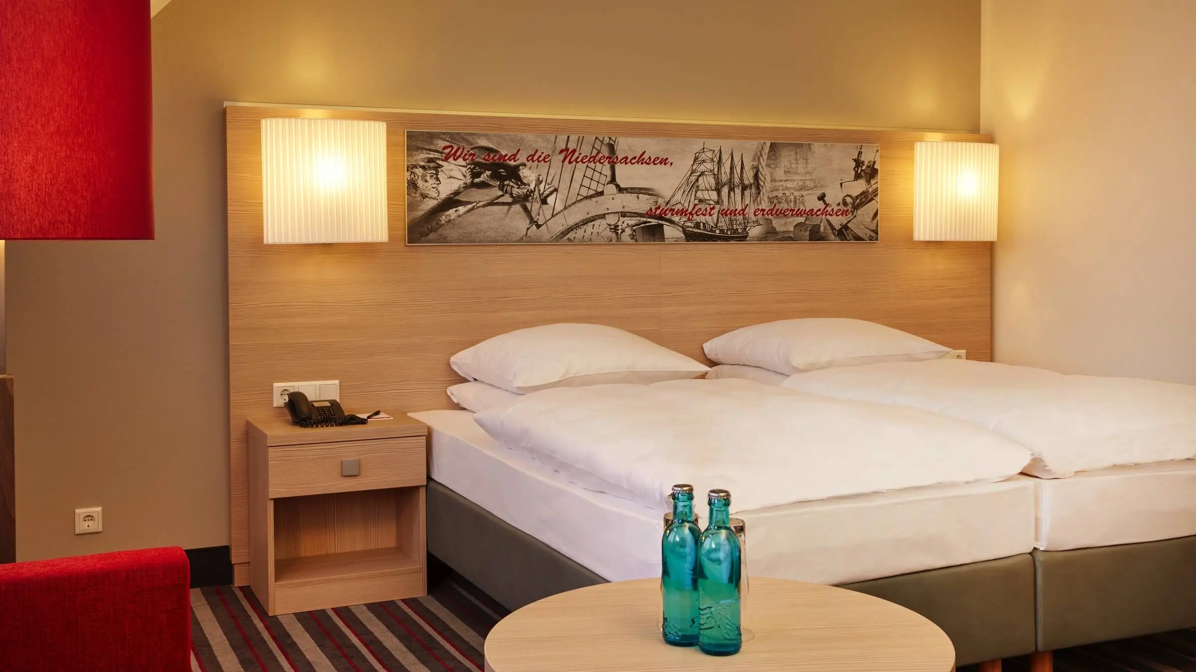 Hotelzimmer mit einem großen Doppelbett. Auf einem Tishc stehen zwei Wasserflaschen.
