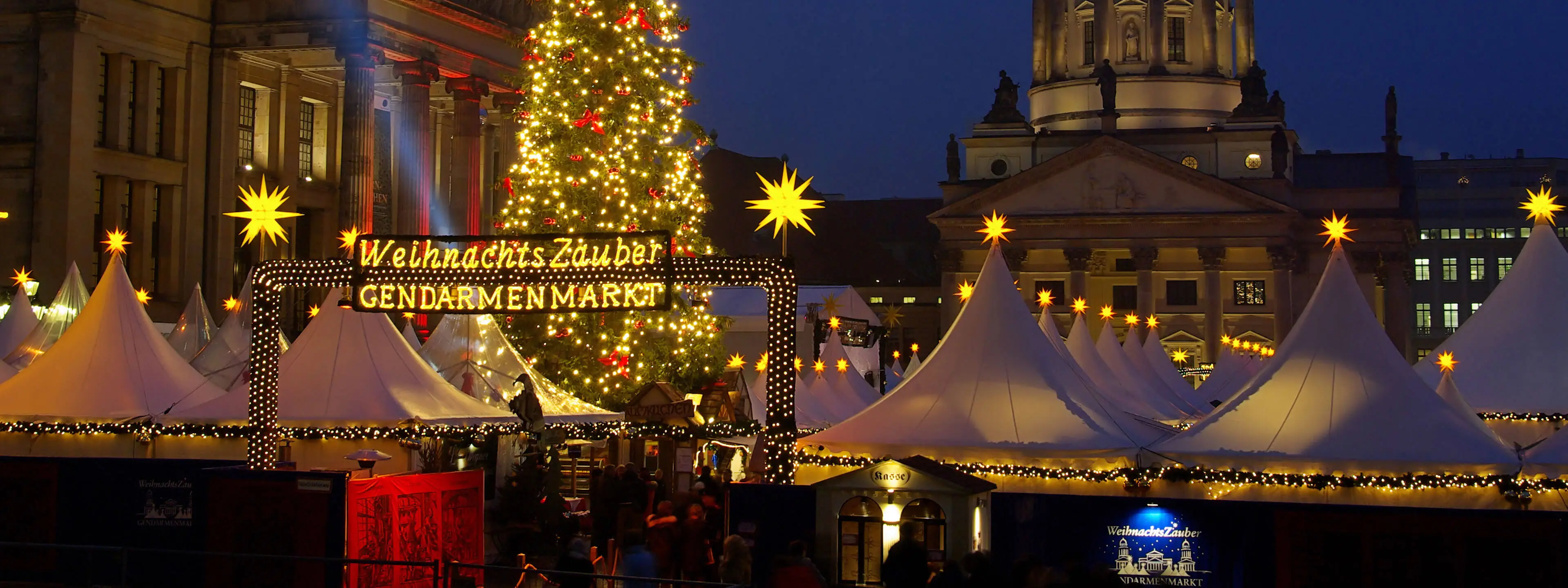 Nahaufnahme vom Weihnachtsbaum und Zelten eines Weihnachtsmarktes.