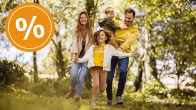 Eine Familie mit zwei kleinen Kindern läuft freudig durch einen Wald.