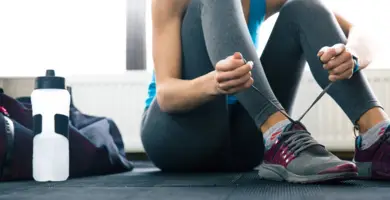 Eine Frau bindet sich im Sportoutfit die Schuhe zu.