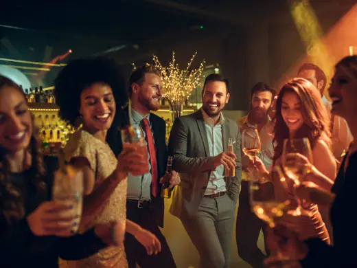 Silvesterparty Viele Menshcne tanzen mit Getränken in einer Bar.