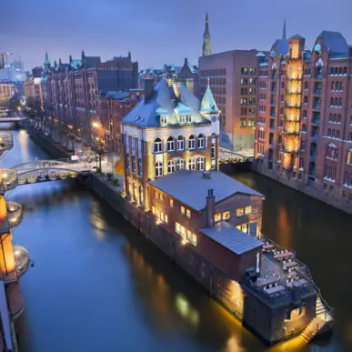 Kanäle von der Speicherstadt bei Nacht. Die Gebäude sind indirekt beleuchtet.