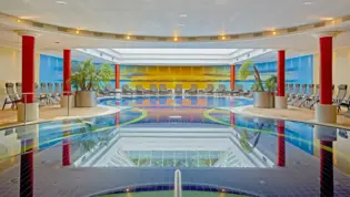Piscina grande con tumbonas en el borde.