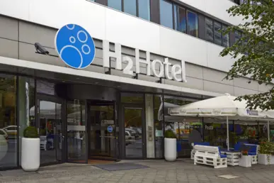 Eingangsbereich vom Hotel mit dem Logo "H2 Hotel" darüber.