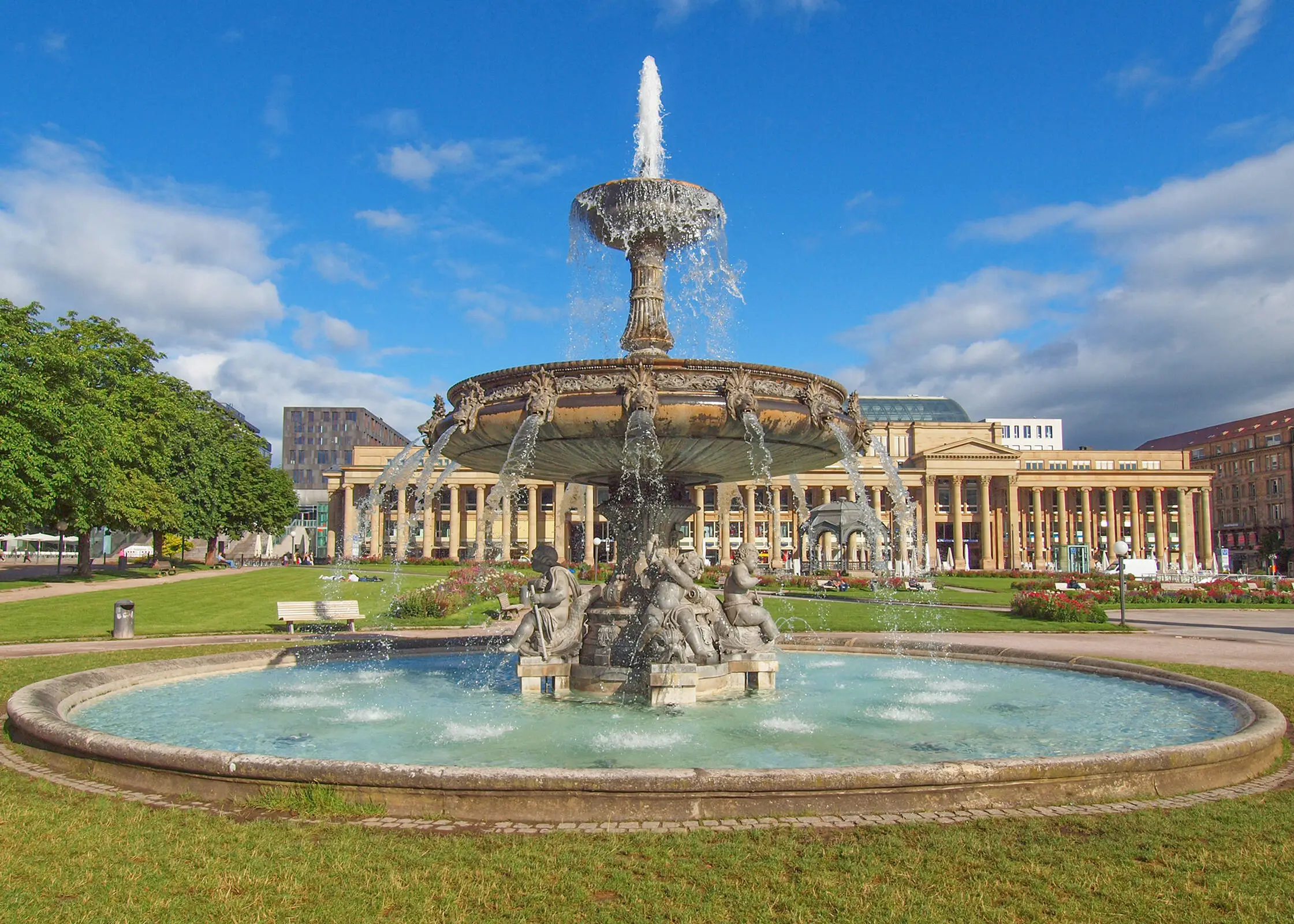 Springbrunnen mit Statuen und 3 Ebenem auf begrüntem Schlossplatz in Stuttgart.