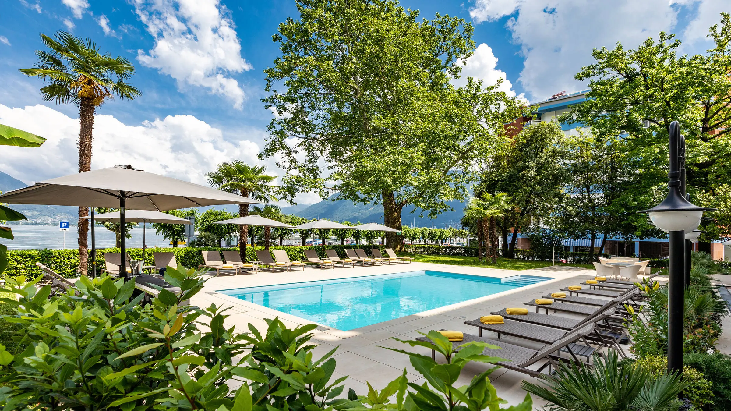 Outdoor pool at the H4 Hotel Arcadia Locarno with palm trees.