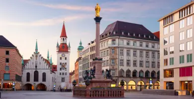 Mariensäule mit goldener Statue auf der Spitze auf dem Marienplatz. Im Hintergrund zahlreiche Geschäfte.