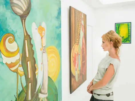 Eine Frau betrachtet Kunstgemälde in einer Galerie. Eine Frau betrachtet Kunstgemälde in einer Galerie.