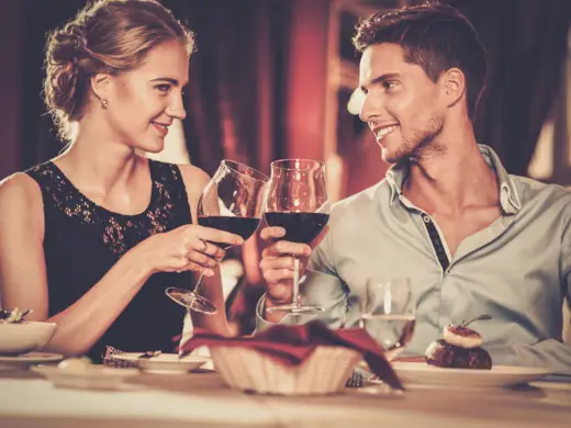 Fancy & Fine 5-Gänge-Menü Ein Paar prostet sich mit Rotwein zu.
