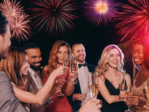 Gruppe von Menschen feiert Silvester mit funkensprühenden Fontänen in den Händen.