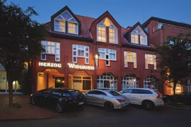 Außenansicht vom Hotel bei Nacht. Vor dem Hotel stehen Fahrzeuge.